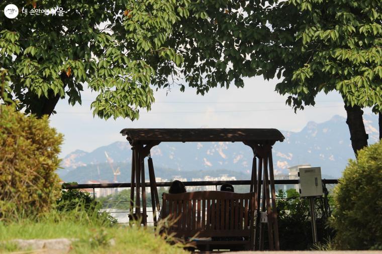 선유도공원 내 카페 옆 그네의자에 앉아 시민들이 한강 풍경을 조망하고 있다. 