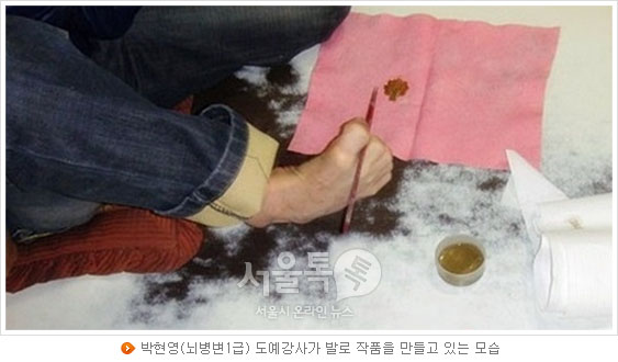 박현영(뇌병변1급) 도예강사가 발로 작품을 만들고 있는 모습
