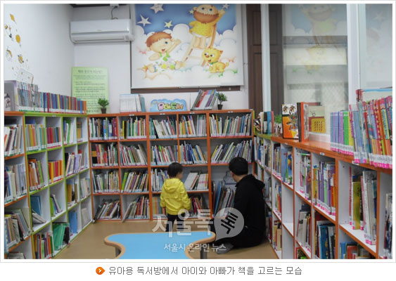 유아용 독서방에서 아이와 아빠가 책을 고르는 모습