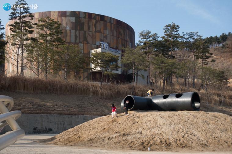 ‘모래 고래 놀이터’에서 마스크를 착용한 아이들이 놀고 있다. 그 뒤에 새롭게 만든 T6-커뮤니티센터가 있다  ⓒ김인수