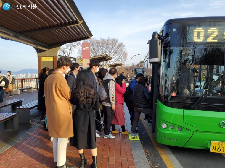 관광객들이 남산타워정류소에서 친환경 02버스를 타고 있다.