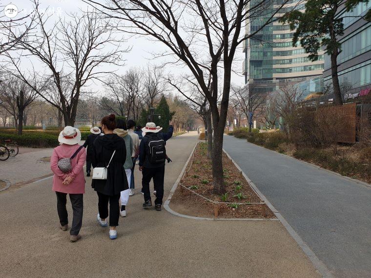서울숲으로 향하는 어르신은 대학생과 나란히 걷고 있다.