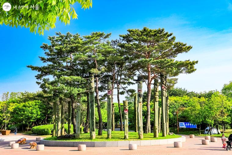 '평화의공원' 산책로 입구에 서 있는 장승들. 주변 나무와 어우러진 모습이 인상적이다. 