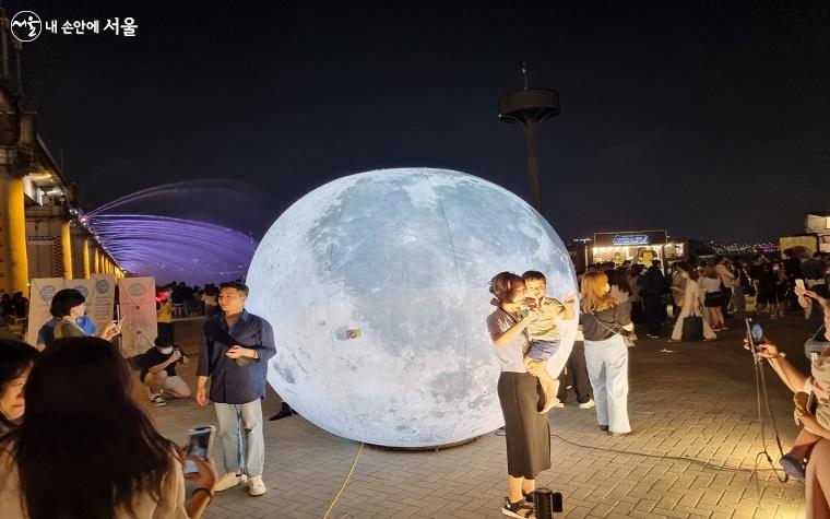 달빛광장의 '보름달 조형물' 앞에서 기념 사진을 찍는 사람들