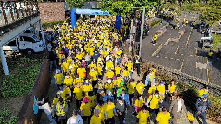 노란 티셔츠로 물결을 이룬 참가자들이 출발선을 통과하고 있다.