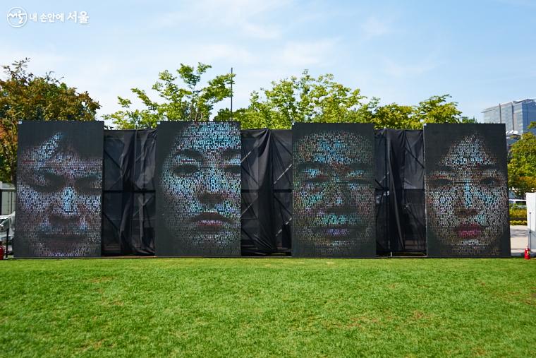 ‘다시 연결된 거리(Distance between US)’ 프로그램 중 하나로 서울광장에 설치된 미디어아트인 ‘페이스 오브 씨티_서울’(이재형 작). 남녀노소의 얼굴, 표정은 서울에서 생성되는 SNS 텍스트로 만들어진다 ⓒ이정규