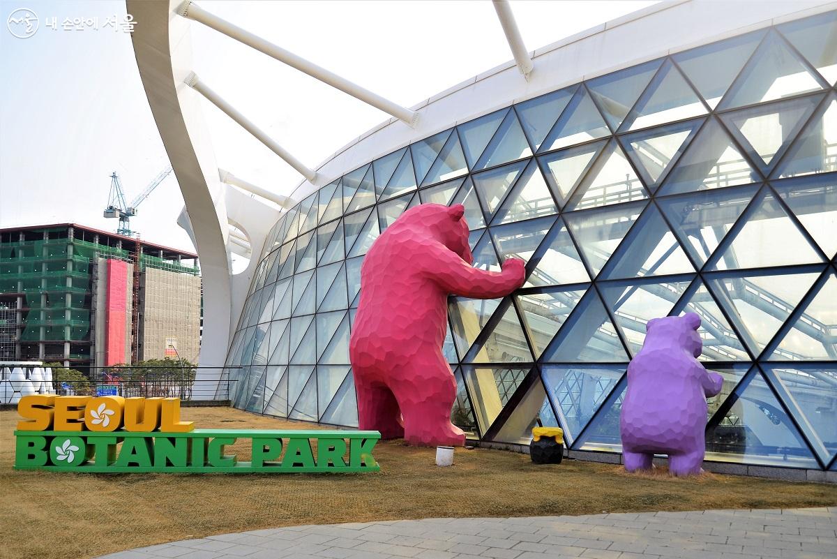 서울식물원 온실 외부 인기 포토존, 곰 두마리가 서울식물원 온실을 내려다보며 안내 로보타닉을 살피고 있다. ⓒ이봉덕
