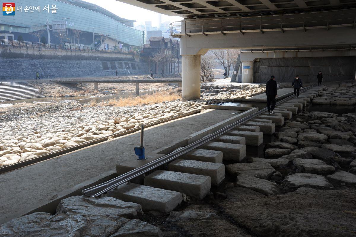 과거 정릉천 자전거도로에서 청계천 자전거도로를 가기 위해서 건너야 했던 징검다리와 청계천을 건너야 했던 보행교의 모습. 둑 위의 푸른색 건물은 청계천박물관이다. ©조수봉