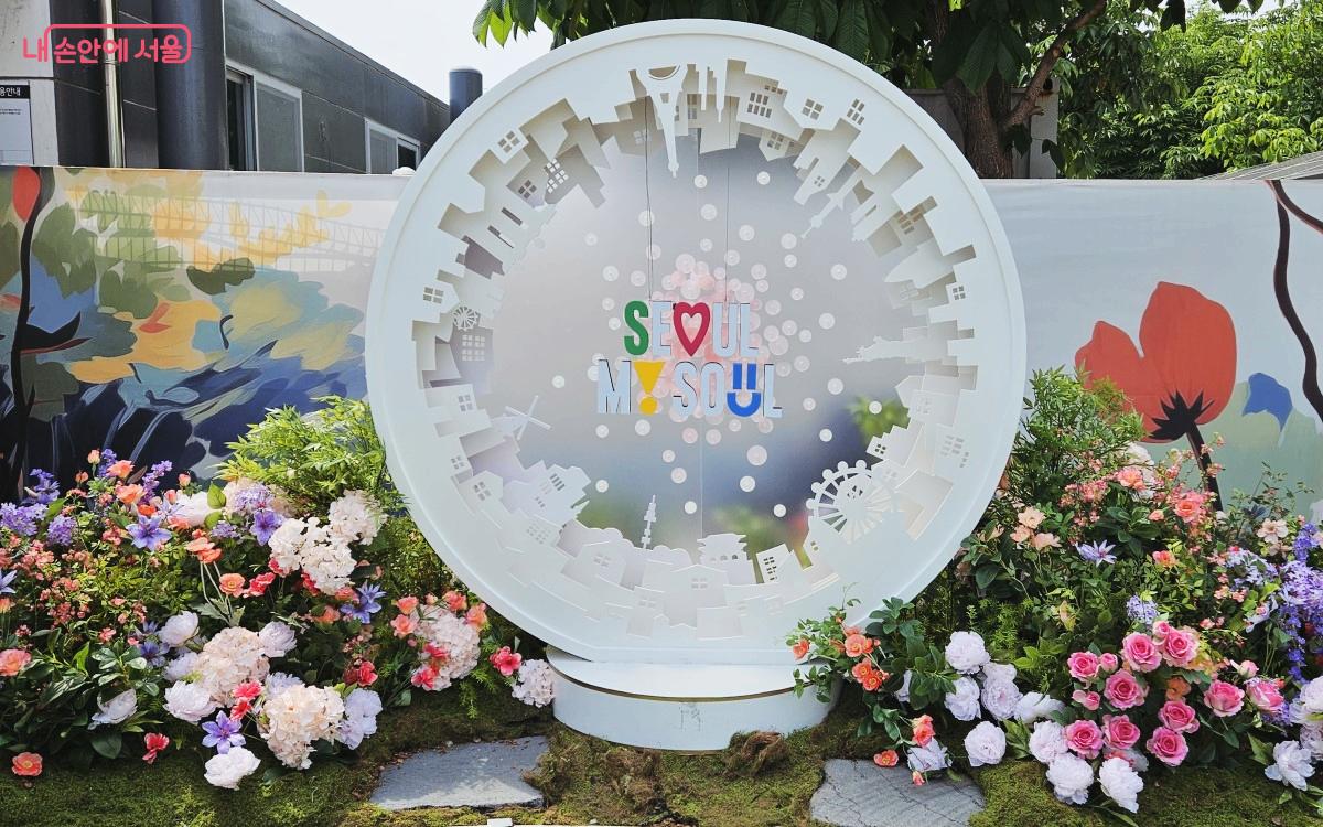 2024 서울국제정원박람회 포토존. 흰색의 스노우볼 모형 근처에 화사한 색의 꽃들이 피어 있다. ⓒ송지혜