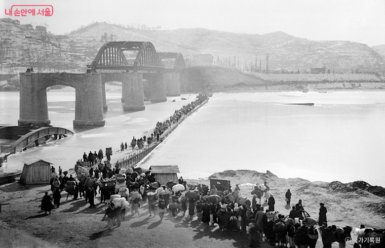 1950년 피난민들이 폭파된 한강 인도교 대신 놓인 부교를 통해 강을 건너는 모습