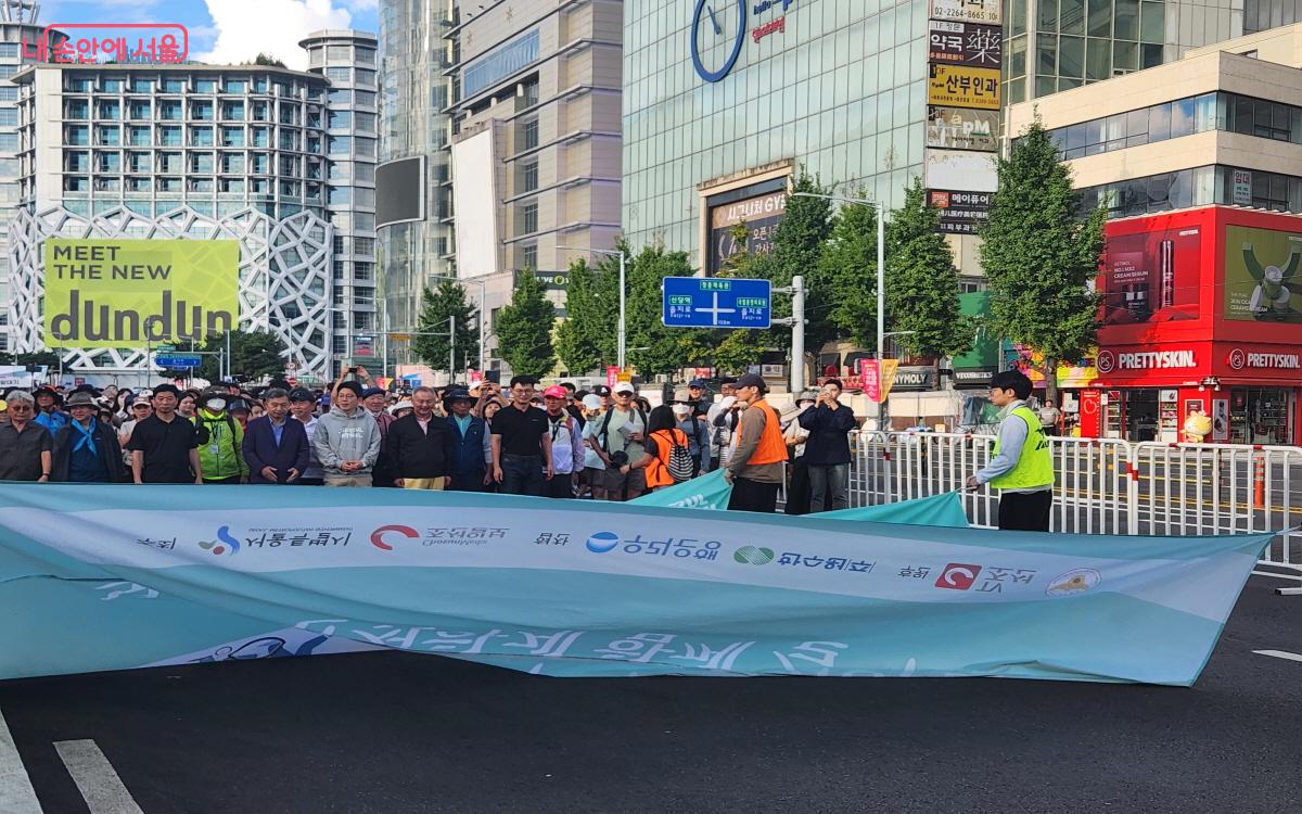 출발 직전 대형 현수막 퍼포먼스를 위해 참가자들이 뒤쪽으로 현수막을 건네주고 있다. ©윤혜숙