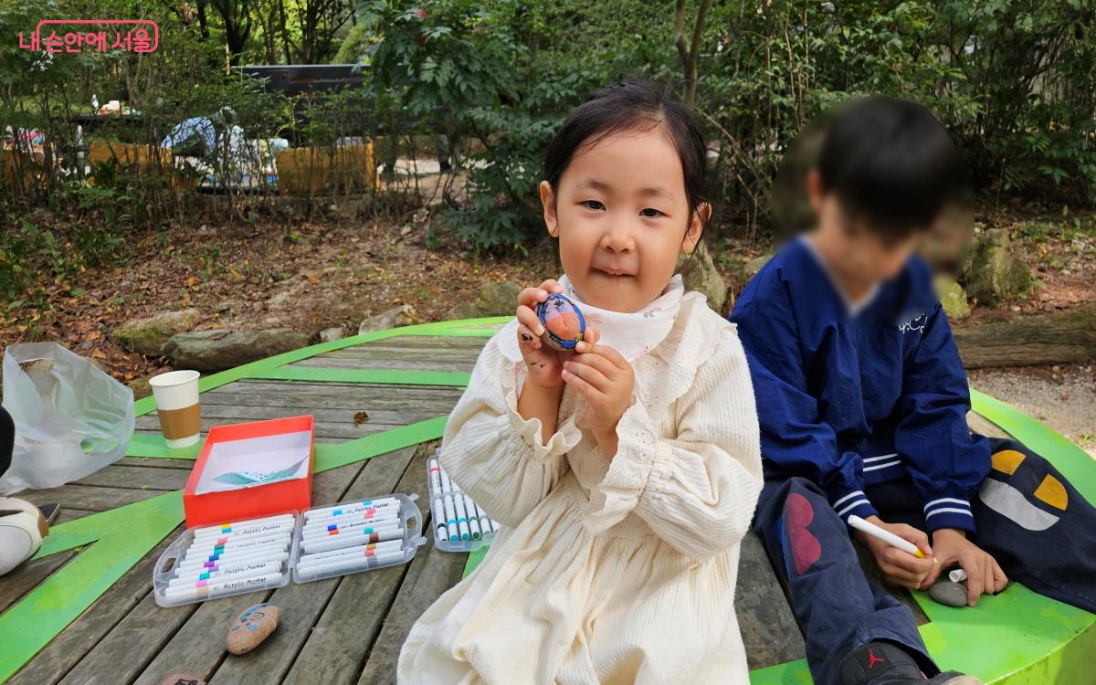 부모님과 함께 온 소율이가 돌멩이 물고기 ‘무무’를 자랑하고 있다. ⓒ이선미