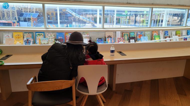 양천공원 도서관을 찾은 엄마와 아이. 창밖으로 놀이터 풍경이 펼쳐진다.
