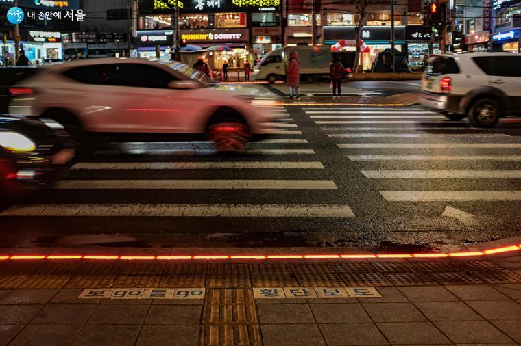 바닥 신호등 LED 패널의 적색으로 차량들이 달리고 있는 모습.