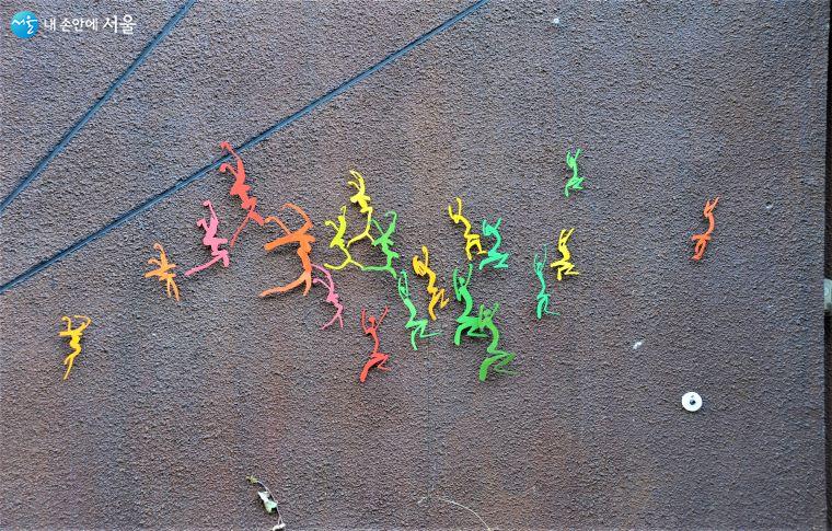 코쿤홀 벽면의 작품. 자세히 보면 ‘봄’자와 ‘꽃’자 도안인데 생동하는 사람의 움직임을 표현한 듯하다 ⓒ조수봉