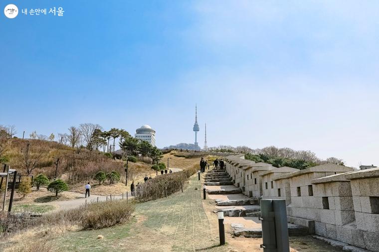 남산 복원사업으로 동상 앞을 잔디 광장으로 다듬고, 땅에 묻혀있던 구간을 원형대로 복원해 만든 백범 광장 성곽길. 