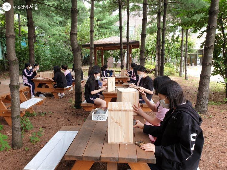 학교 안 잣나무 숲속에 원목 테이블을 설치해 ‘숲속 메이커교실’을 열었다.