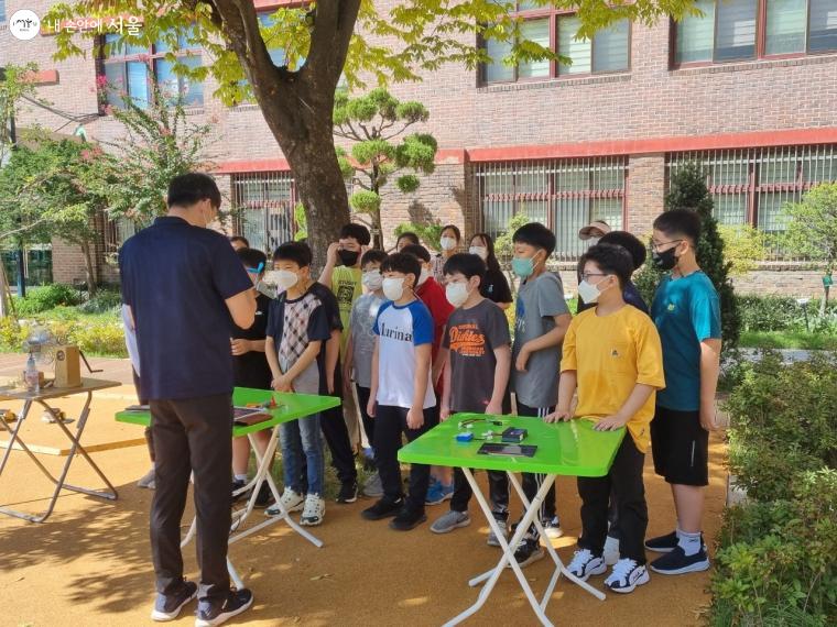 서울대명초에서 선생님이 태양광 자동차 키트 조립 방법을 설명하고 있다. 