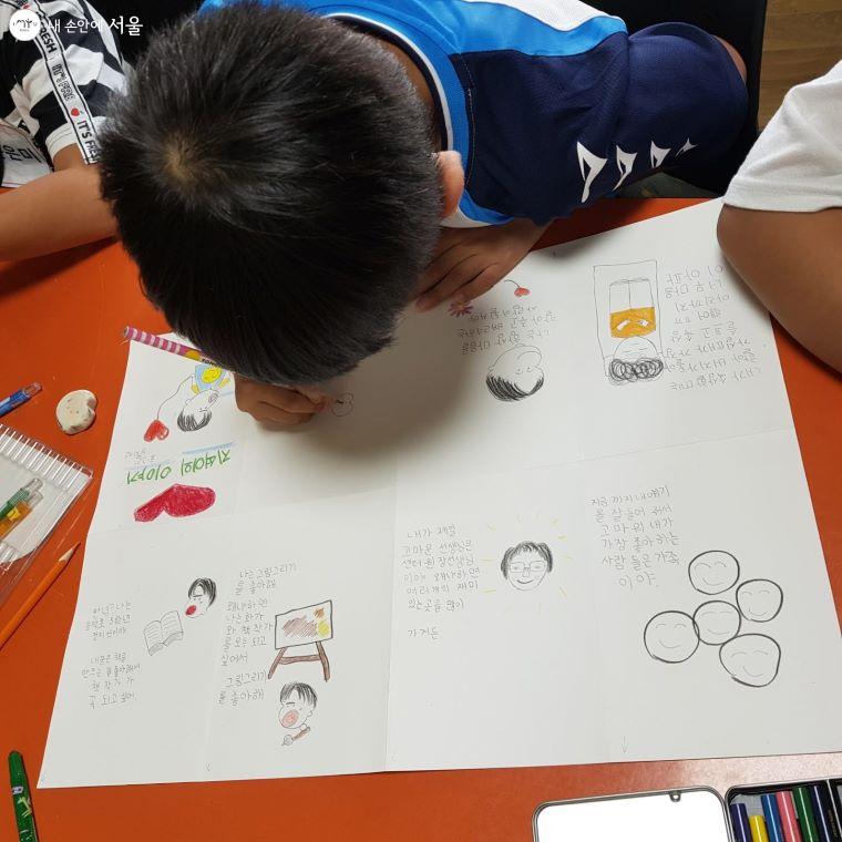 아이가 자리에서 그림책을 만드는 데 열중하고 있다. 