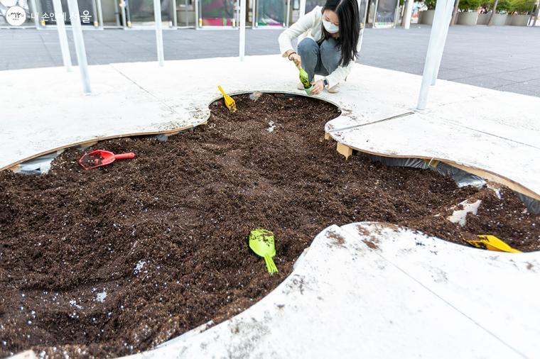 한 시민이 화분 하나를 떼어 흙을 담고 있다 ⓒ문청야