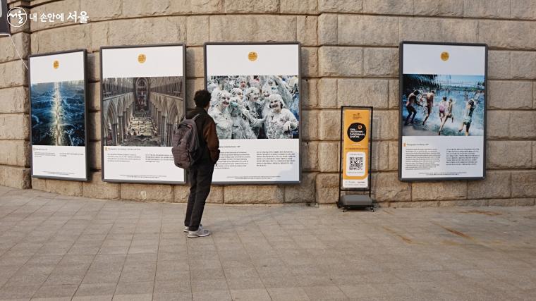 한 시민이 서울도서관 외벽의 ‘2021 서울글로벌 포토저널리즘 사진전’을 들여다보고 있다. ⓒ이선미 