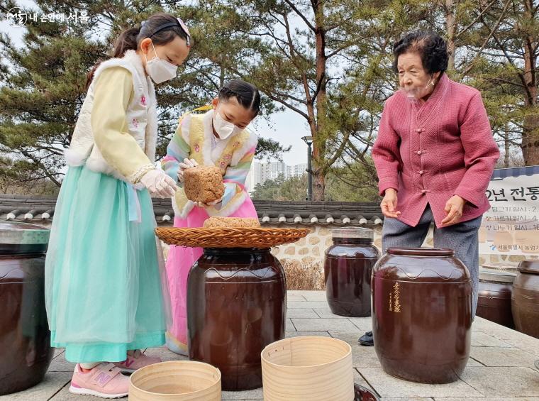 참가자들과 명인이 깨끗하게 씻은 메주를 항아리에 담고 있다. 