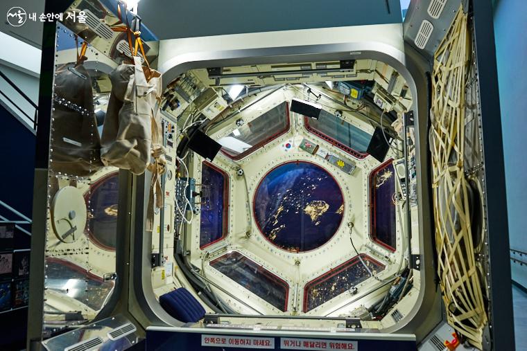 지구궤도를 돌고 있는 국제우주정거장의 관측용 모듈인 큐폴라를 재현한 세트. 가운데 창 너머로 한반도의 야경이 보인다. B전시실 밖 SF존 ⓒ이정규