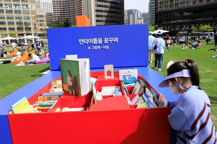 파란색의 그림책·아동 코너에서 책을 고르고 있는 아이의 모습. 누구든 자유롭게 책을 빌려 읽을 수 있다. 