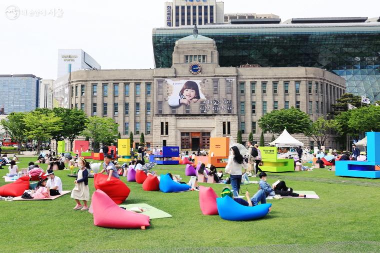 서울광장 잔디밭에 누워 책을 읽고 쉼의 시간을 갖는 시민들의 모습