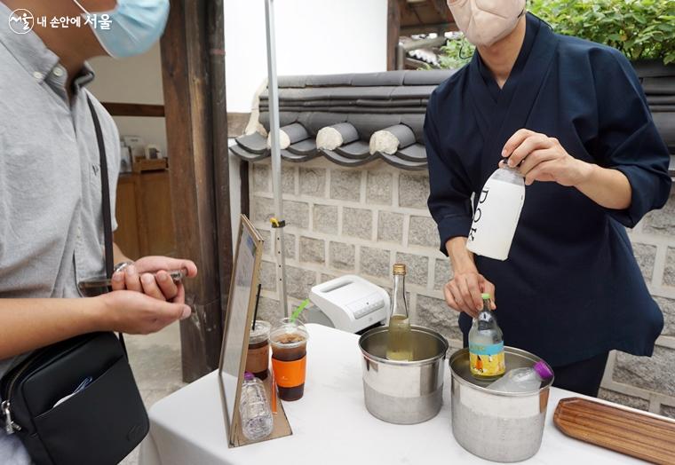 담당자가 외국인에게  우리술을 설명하고 있다.