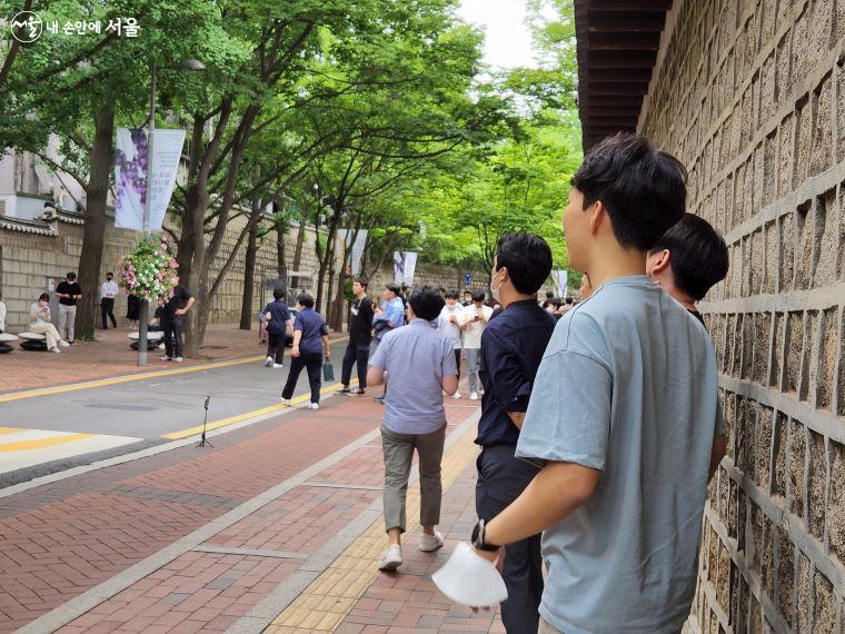 덕수궁 담벼락에 늘어선 직장인들이 기타로로의 공연을 구경하고 있다. ⓒ윤혜숙