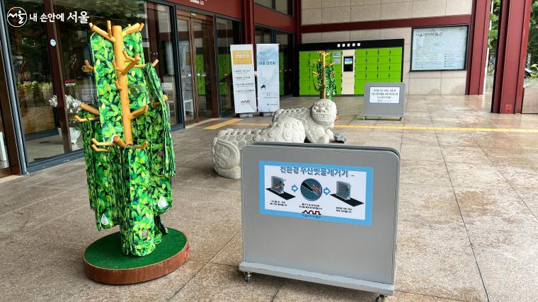 박물관 문 앞에 있는 '친환경 우산 빗물제거기'와 '재사용 우산커버'