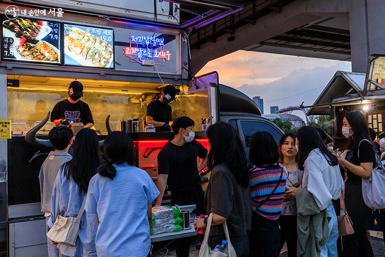 주변이 어둑해질 무렵 푸드트럭 앞에서 음식을 기다리는 시민들 ©유서경 