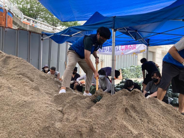 봉사자들이 모래를 쉽게 담을 수 있게 골고루 모래를 배분하고 있다. ⓒ전주영