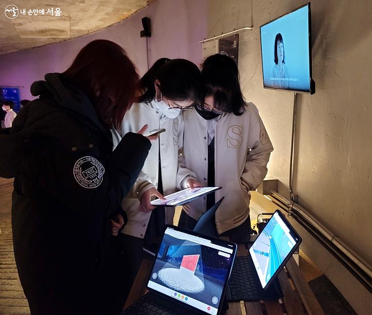서울예술고등학교 학생들이 김세진 작가와 협업해 만든 자신들의 작품 <메타버스-서울 램프 시간 박물관>을 보고 있다.