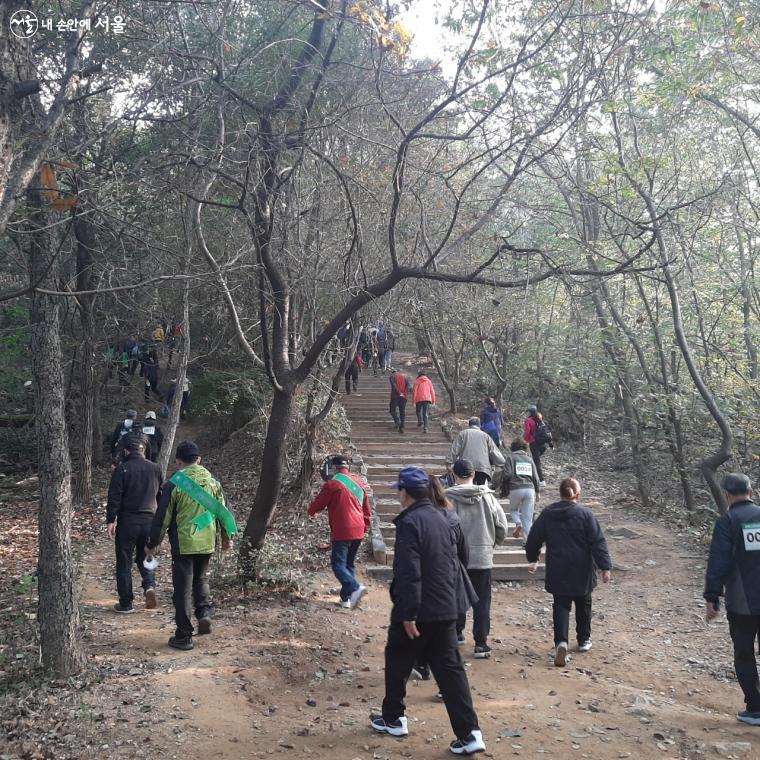 흙길과 돌 계단을 오르고  있는 시민들 모습