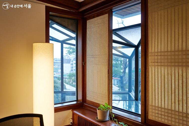 창호지를 바른 미서기창 너머에 2층까지 다다른 온실 창이 보인다. 