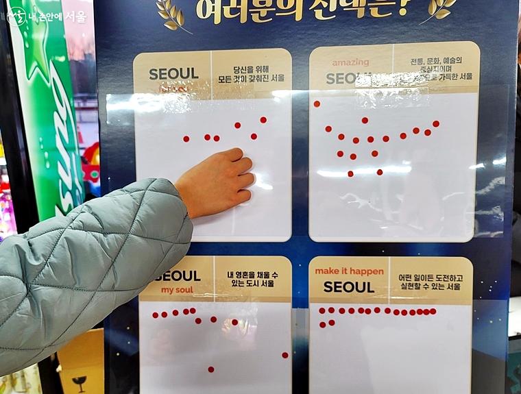 한 시민이 마음에 드는 서울 브랜드 슬로건에 스티커를 붙이고 있다. ⓒ김윤경