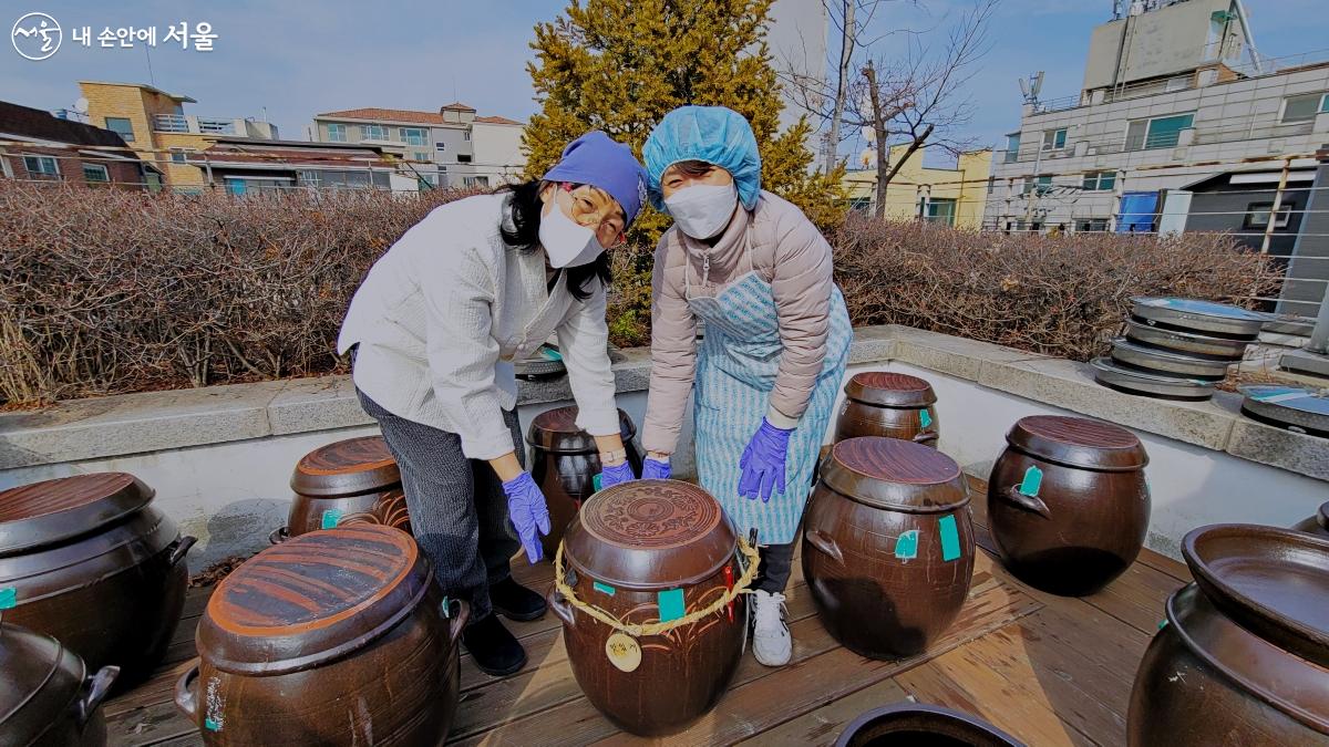 항아리 둘레에 새끼를 꼬아 만든 금줄을 치고 주민들이 활짝 웃고 있다. ©박분