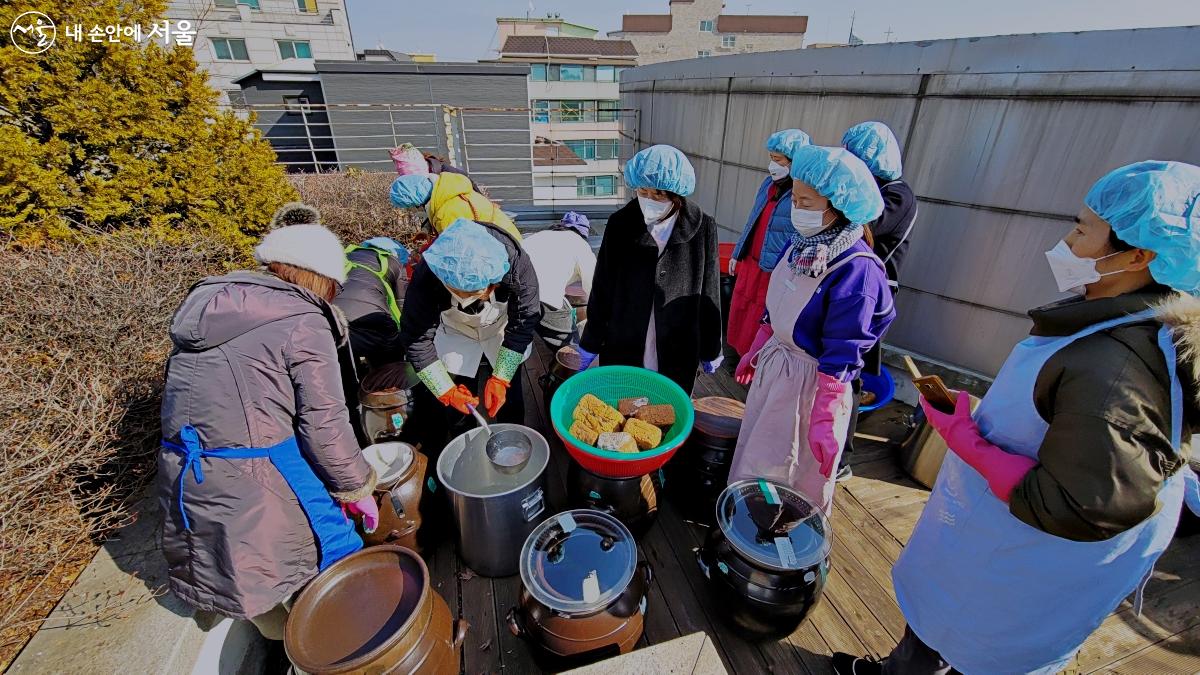 장 담그는 과정을 프로그램 참가자들이 진지한 표정으로 바라보고 있다. ©박분