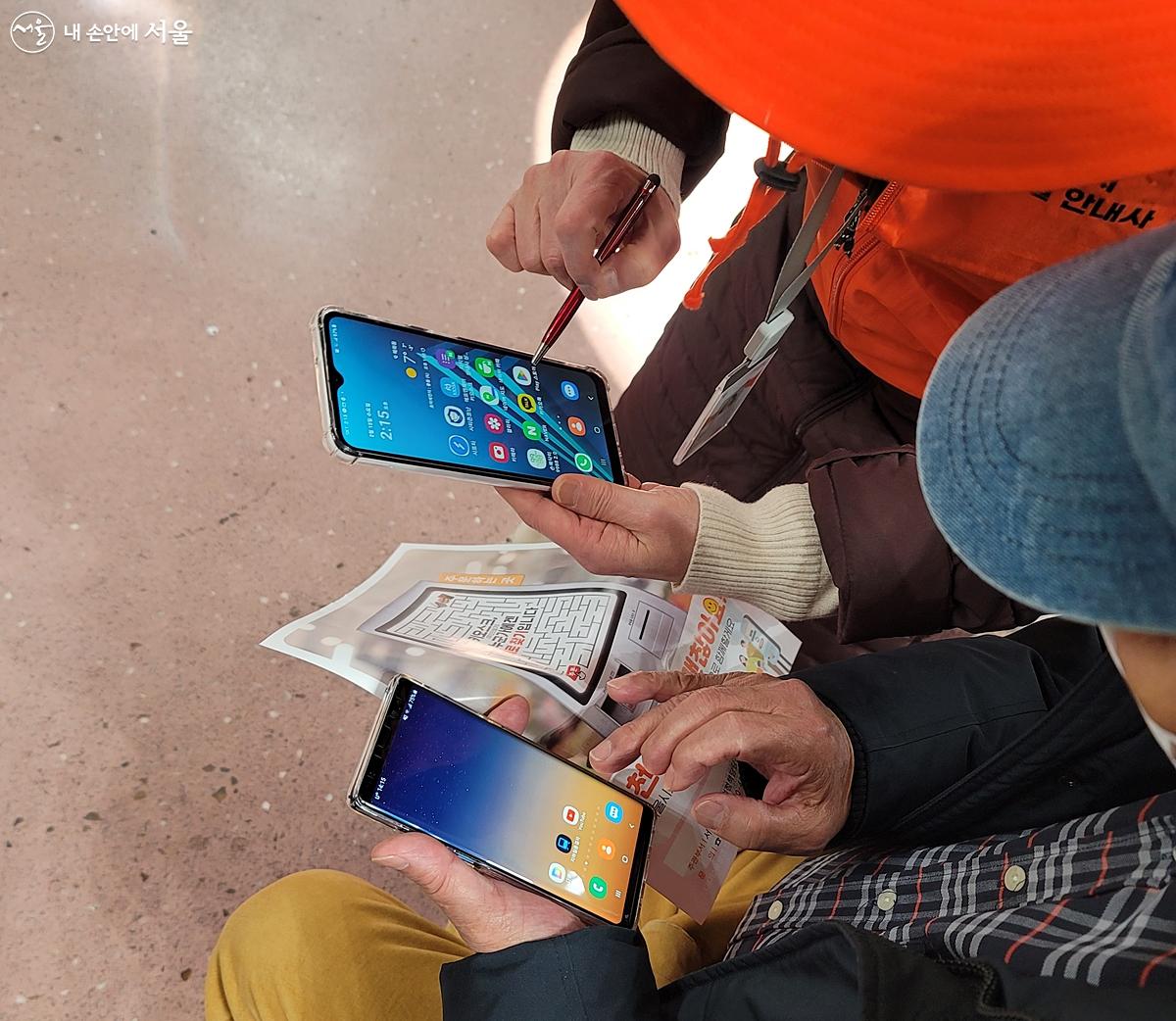 디지털 안내사가 자신의 스마트폰으로 어르신에게 사용법을 보여드리고 있다. ⓒ김윤경