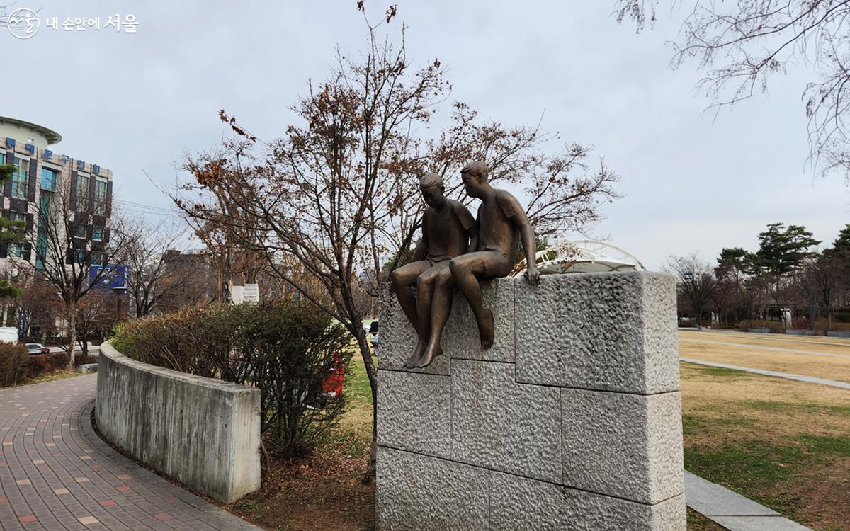 석재 조형물과 그 위에 앉아 대화하는 두 소년의 청동 조각상 ©김미선