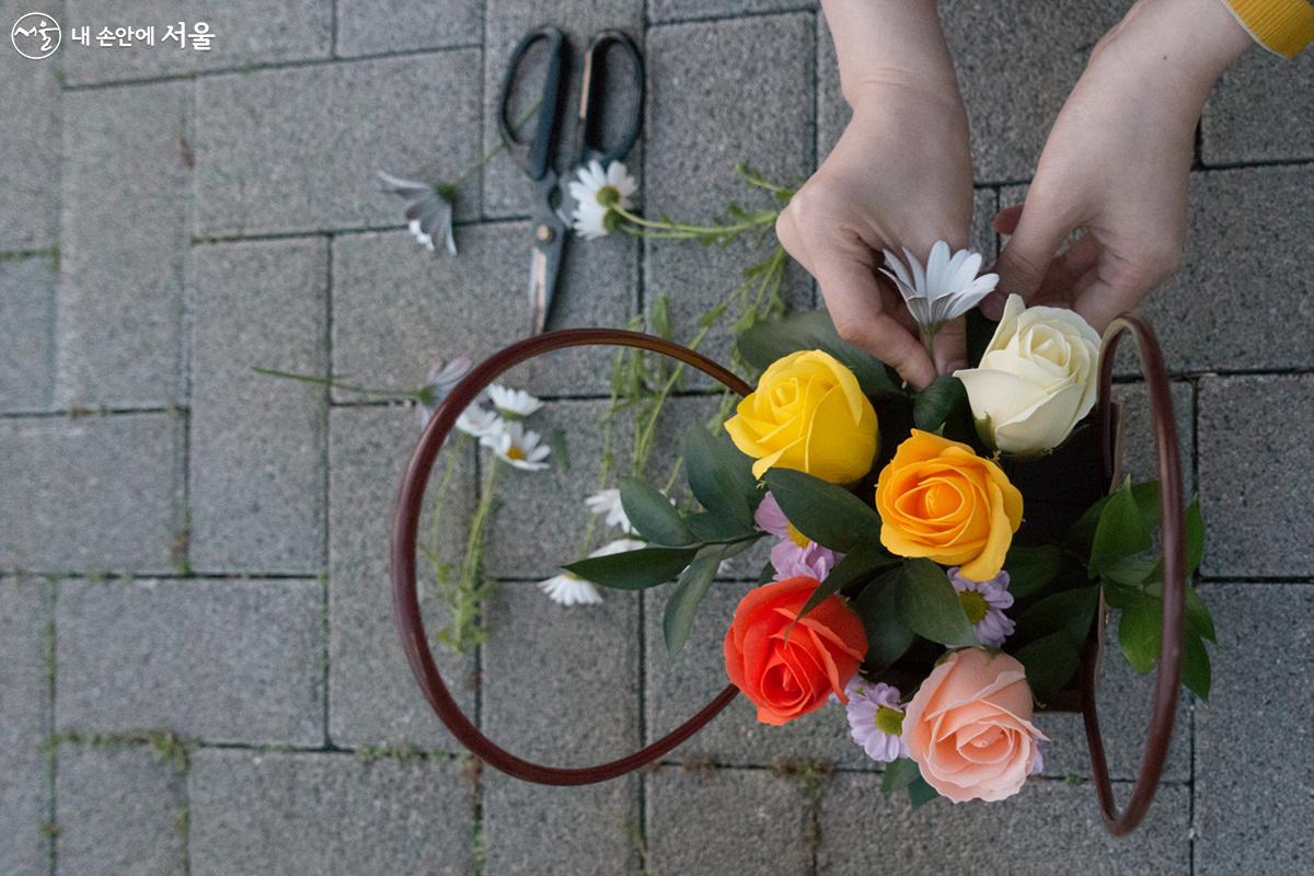 야외 화단에서 꽃꽂이용으로 자른 꽃을 꽃바구니에 정리하는 참가자 ©김인수 