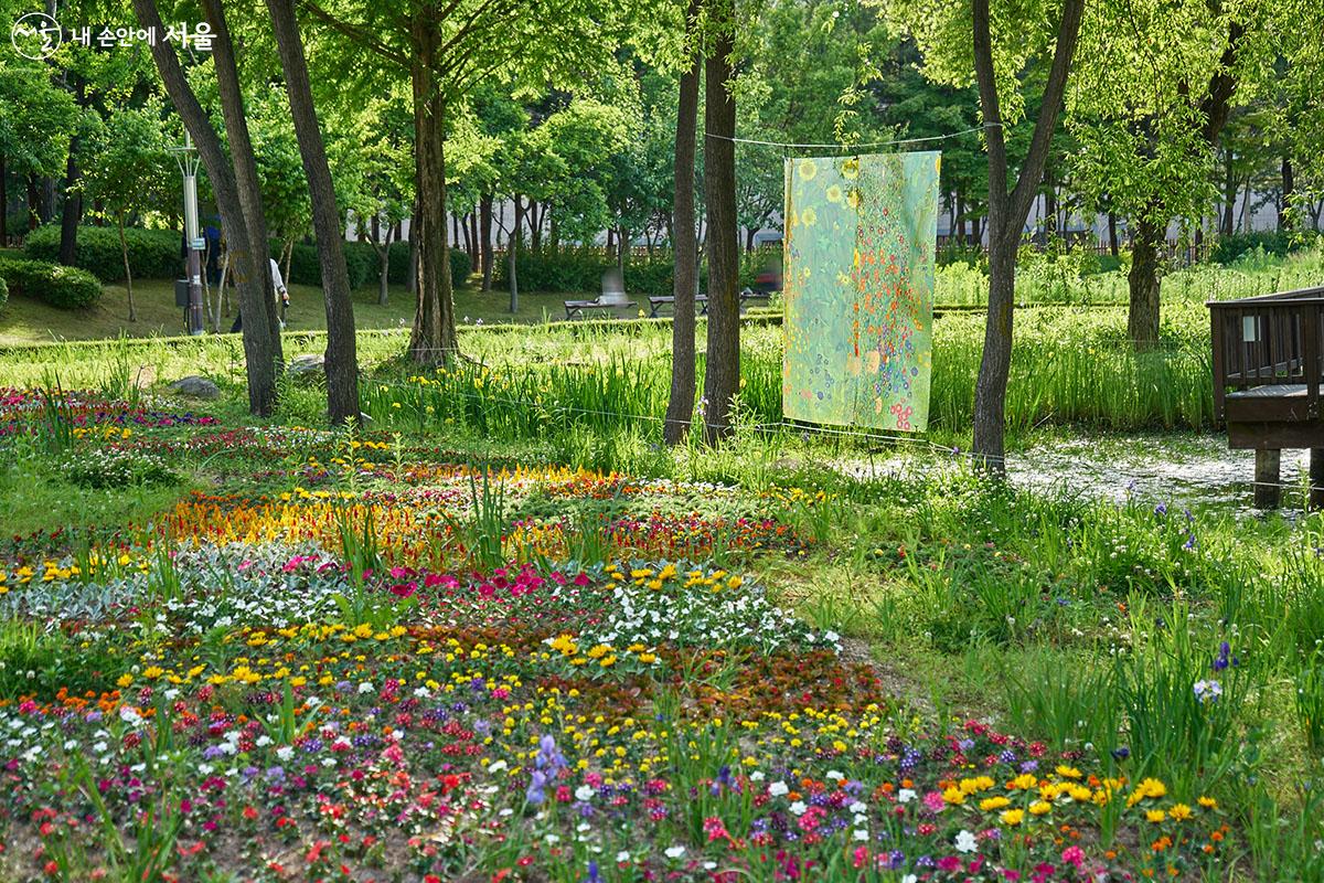 구스타프 클림트의 <꽃이 있는 농장 정원>. 그림 앞에 화사하게 피어있는 다채로운 빛깔의 실제 꽃들과 멋진 조화를 이룬다. ⓒ이정규