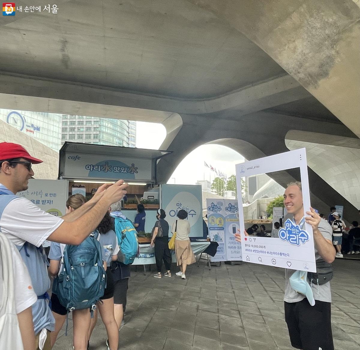 ‘맛있는 아리수’ 포토 프레임을 들고 사진을 찍는 외국인 관광객들의 모습 ⓒ이정민