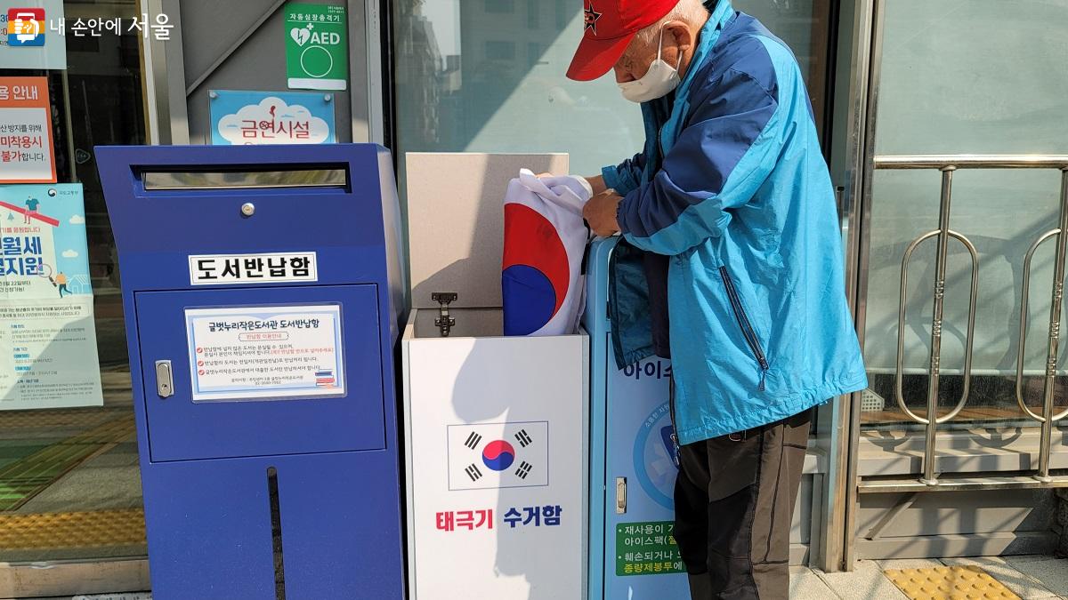 동주민센터에 있는 태극기 수거함에 한 주민이 낡은 태극기를 넣고 있다. ©박분