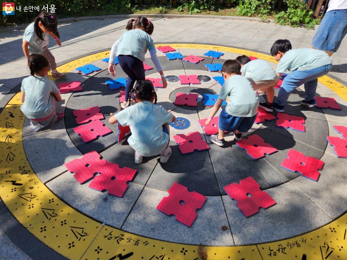 아이들이 둥근 바닥에 놓인 판을 뒤집어서 같은 편의 색이 많이 나오는 게임을 하고 있다. ⓒ윤혜숙