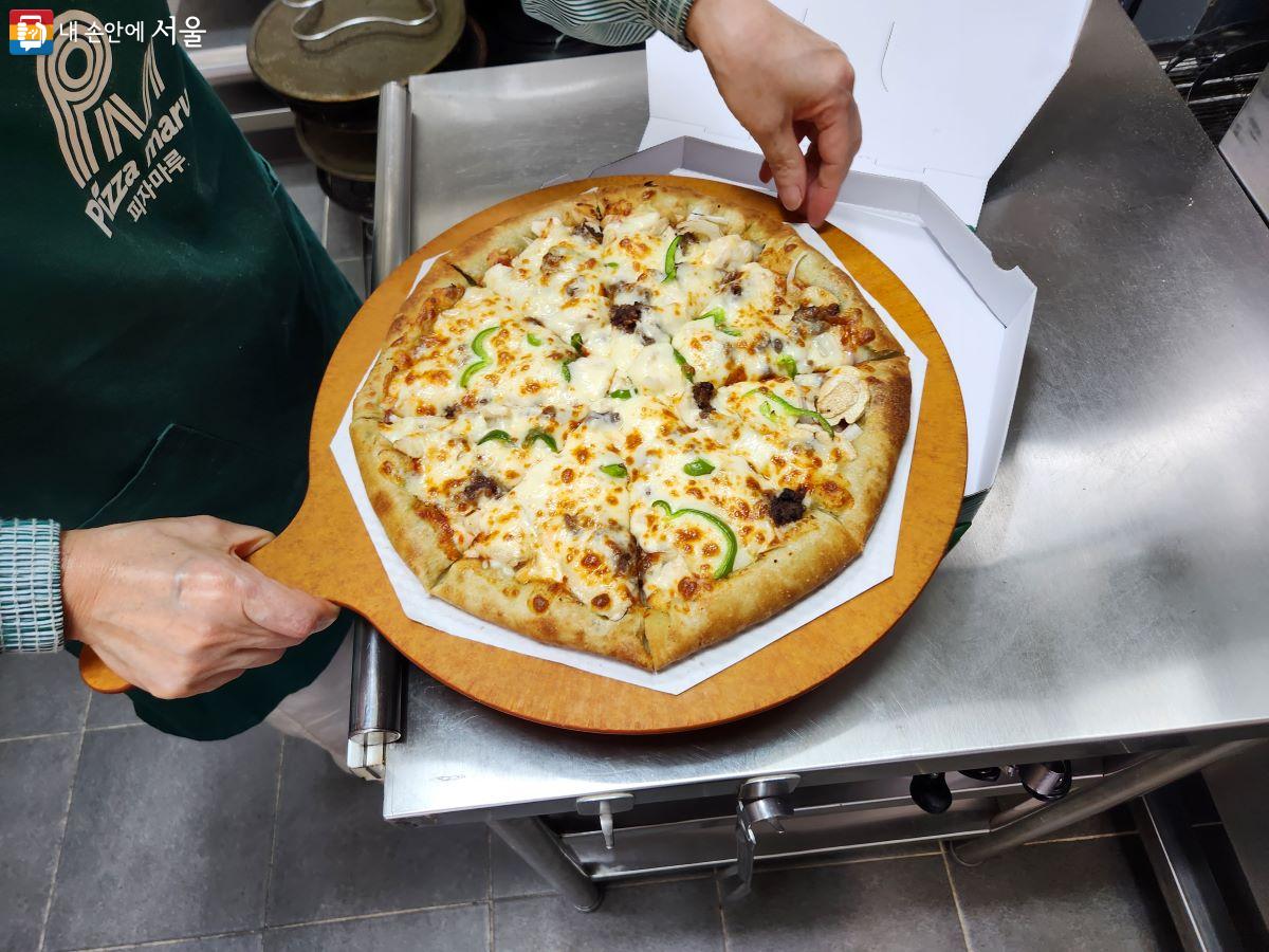 피자 가게에서 일하는 시니어가 주문 받은 피자를 완성한 뒤 포장하고 있다. ©윤혜숙
