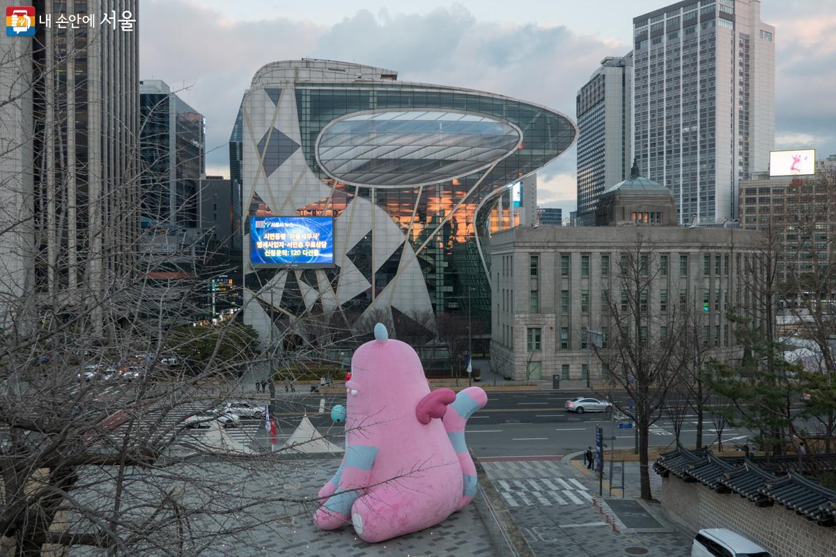 노을을 품은 서울시청사와 그 앞에 전통 색상인 단청(丹靑)의 붉은색을 현대적으로 재해석해 차분한 ‘분홍색’으로 바뀐 대형 아트벌룬 해치  Ⓒ김인수