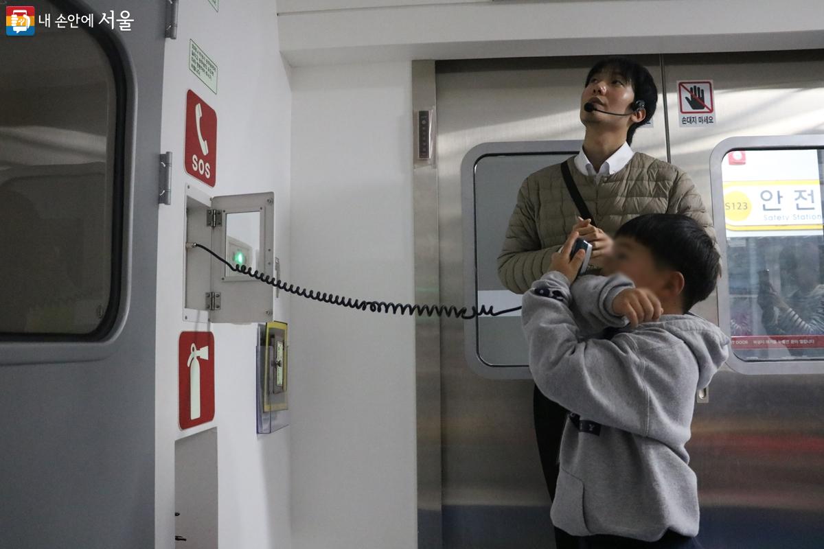 어린 교육생이 지하철 내 비상 전화기를 이용하여 구조 요청을 하고 있다. ©강사랑